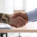 soldier and businessman shaking hands indoors, closeup