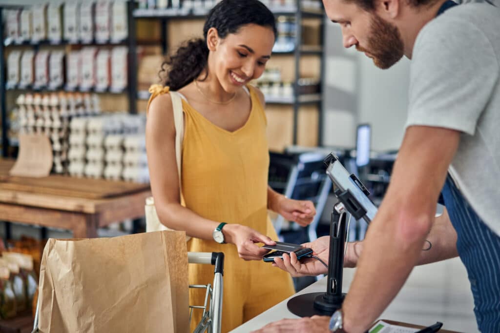 Photo of a young woman paying with a credit card in an organic store